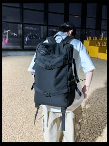 Man met een grote zwarte outdoor wandelrugzak in een stedelijke stadionomgeving