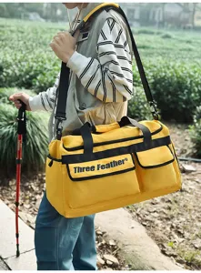 Modell trägt eine große gelbe Reisetasche mit Seitentaschen und schwarzen Gurten.