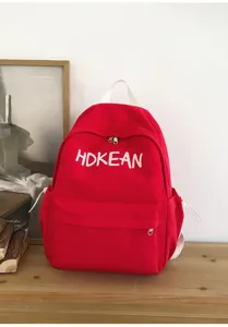 Vue détaillée d'un sac à dos d'écolier rouge avec broderie de lettres blanches