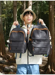 Sacs à dos scolaires élégants à carreaux portés par un mannequin dans une forêt dense.