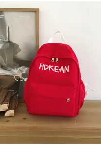 Vue détaillée de ce sac à dos scolaire rouge vif avec une broderie de lettres blanches.