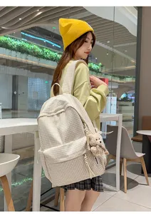 Détail d'un sac à dos à carreaux de style académique avec un charmant ours mignon