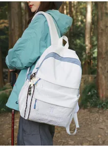 Détail d'un sac à dos blanc de grande capacité porté par un modèle dans une forêt.