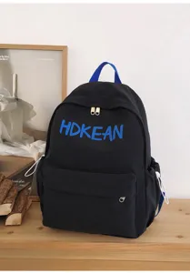 Gros plan d'un sac à dos d'écolier noir avec broderie 'HDKEAN' bleue sur table en bois