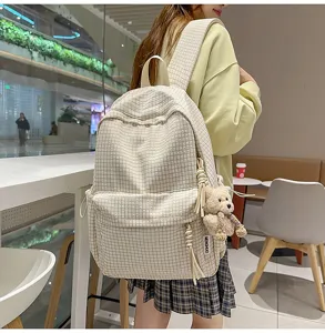 Vue détaillée d'un sac à dos à carreaux beige avec un adorable porte-clés ours