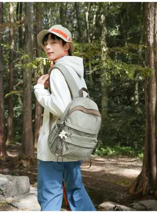 Vue extérieure d'un sac à dos à carreaux verts sur un mannequin en milieu forestier.
