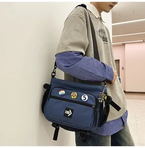 Close-up detail of a blue Korean-style canvas messenger bag with pins worn by a male model