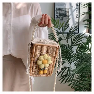 Gros plan sur un sac carré en rotin tissé à la main avec fleur crochetée et perles