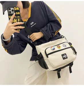 Detail view of the cream canvas messenger bag with stylish badges and logo patch