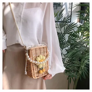Détail du sac en rotin tressé avec fleur au crochet et bandoulière en perles.