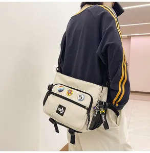 Cream-colored large capacity workwear messenger bag decorated with trendy pins and strap
