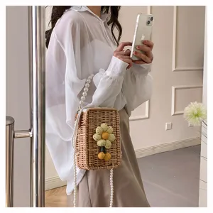 Détail de mode d'un sac en paille tissée avec fleur au crochet et bandoulière perles