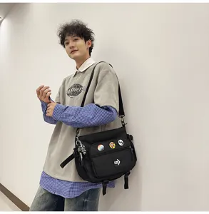 Man wearing black Korean style workwear messenger bag with badges and astronaut charm