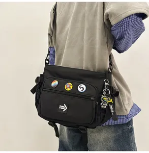 Detailed view of a large black messenger bag with decorative badges and keychain