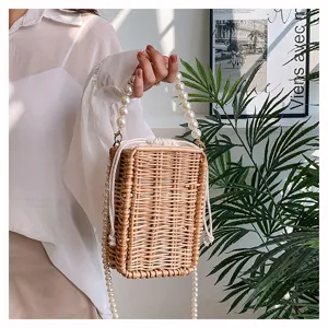 Détail d'un sac en osier rectangulaire avec d'élégantes poignées et chaîne en perles