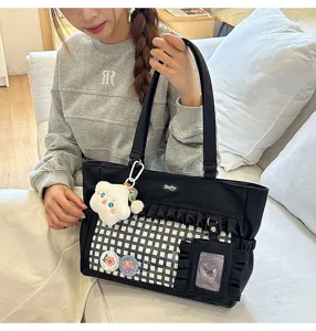 Detailansicht der schwarzen Itabag mit Rüschen, klarem Fenster und Plüsch-Anhängern.