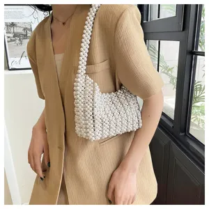 Detailansicht einer handgefertigten weißen Perlen-Unterarmtasche zu einem beigen Blazer.