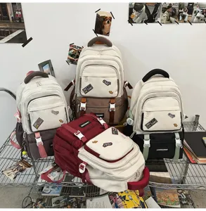 Various colors of stylish contrast school backpacks with cute patches displayed on a metal shelf.