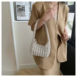 Detail einer handgefertigten gewebten weißen Perlen-Unterarmtasche auf Khaki-Outfit.