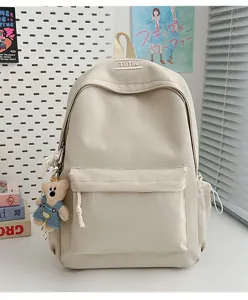 Vue lifestyle d'un grand sac à dos crème pour étudiant avec breloque ours en peluche