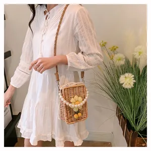 Détail d'un sac en paille tressée avec fleur en maille et anse élégante en perles.