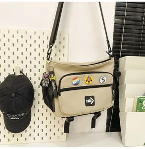 Detailed view of a khaki Korean style utility messenger bag with decorative patches and charms