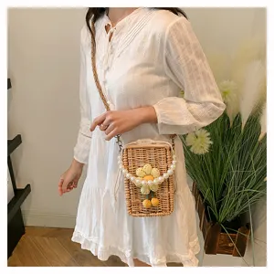 Petit sac bandoulière en rotin tressé avec fleur et perles porté par un mannequin