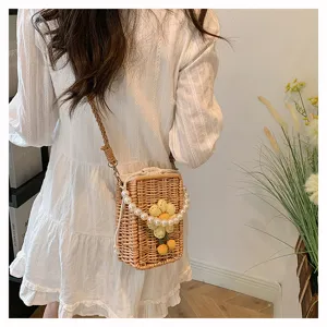 Vue détaillée d'un sac en paille tissé avec chaîne de perles et fleur jaune décorative.