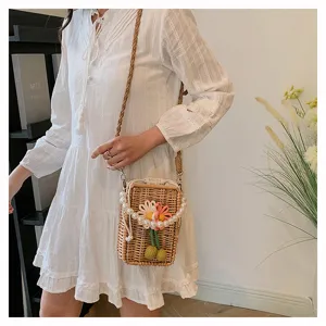 Sac bandoulière en osier tissé main avec fleur et chaîne perles, porté à l'épaule