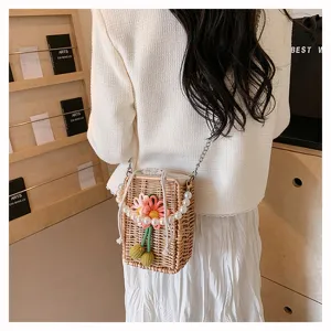 Vue de dos d'une femme portant un mini sac en paille avec chaîne perles et fleur rose