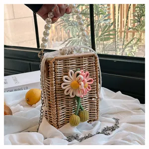 Vue détaillée d'un sac en rotin tressé avec fleurs décoratives et une poignée en perles.