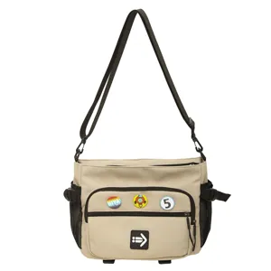 Detail view of khaki workwear messenger bag with decorative badges and mesh pockets
