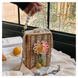 Détail de ce sac panier en osier tressé à la main avec poignée en perles et ornement floral coloré