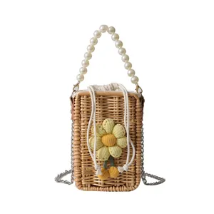 Vue détaillée d'un petit sac en paille fait main avec fleur et poignée en perles