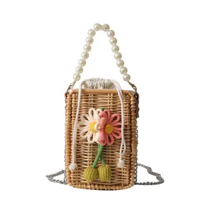 Petit sac carré en rotin tressé à la main avec poignée en perles et décors floraux.