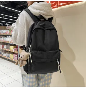 Vue détaillée d'un sac à dos noir de style collège avec un ours en peluche dans un magasin