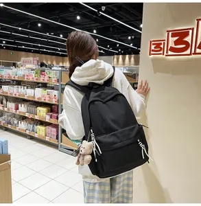 Vue arrière d'un sac à dos scolaire noir de grande capacité avec un porte-clé ours.