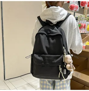 Photo de style de vie d'un sac à dos scolaire texturé noir avec un joli breloque ours en peluche