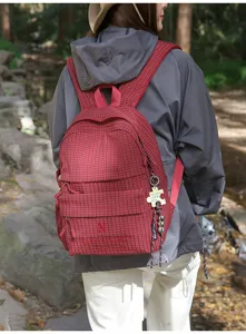 Sac à dos décontracté à carreaux rouges et blancs porté par un mannequin en forêt