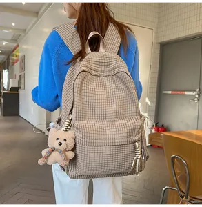 Détail d'un sac à dos à carreaux marron vintage avec un charmant ours en peluche