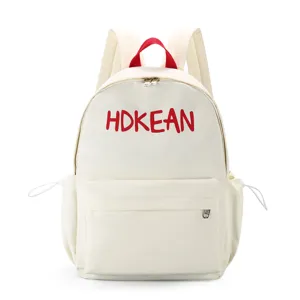 Vue de face du sac à dos scolaire crème avec broderie HDKEAN rouge et poignée supérieure