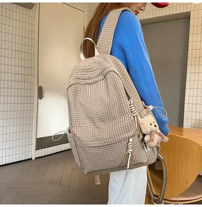 Modèle portant un sac à dos à carreaux marron clair avec un joli porte-clés ours en peluche