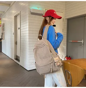 Sac à dos d'écolier à carreaux beige avec ourson dans un couloir d'école
