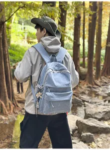 Sac à dos scolaire à carreaux bleus avec broderie MARS SOCIETY dans une forêt.