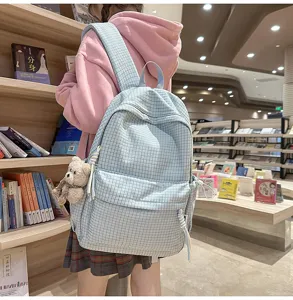 Vue détaillée d'un sac à dos d'école à carreaux bleu clair porté par une étudiante en librairie