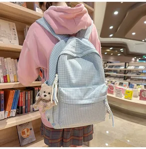 Vue détaillée d'un sac à dos d'étudiant à carreaux bleu clair avec un porte-clés ours