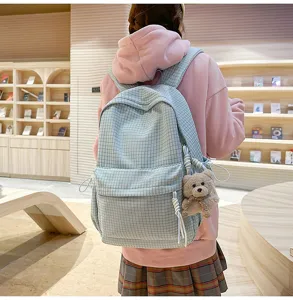 Vue arrière d'un sac à dos d'école bleu clair à carreaux avec ours en peluche