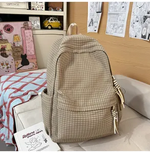 Vue détaillée d'un sac à dos à carreaux de style collégial avec pompons décoratifs