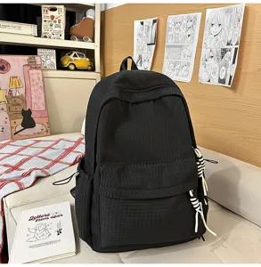 Vue détaillée du sac à dos noir texturé à carreaux dans un décor de chambre douillet.