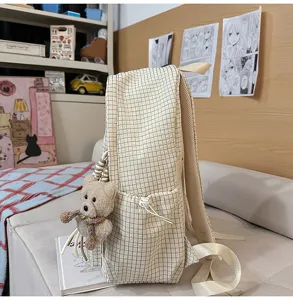 Vue détaillée de côté d'un sac à dos à carreaux crème avec un petit ours en peluche